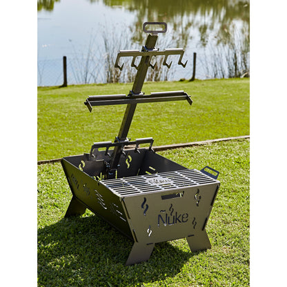 Portable grill with 'Nuke' branding on a grassy area by a body of water.
